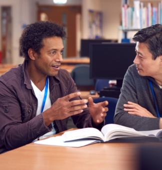 A male teacher talks to male teacher in the library
