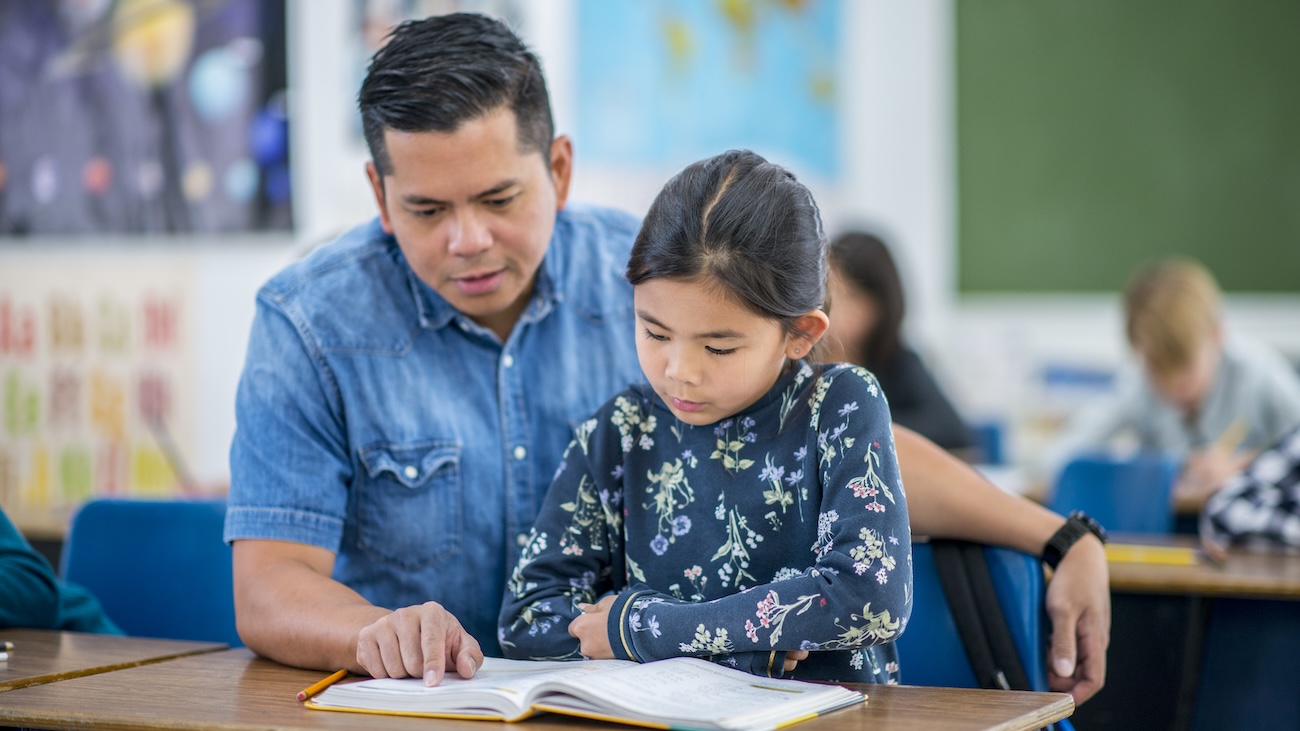 Male teacher reading with a young girl