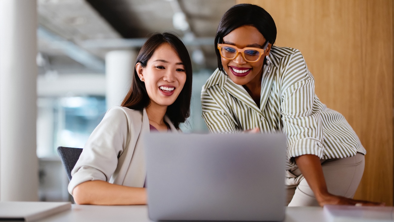 Two female teachers having a conversation around a laptop